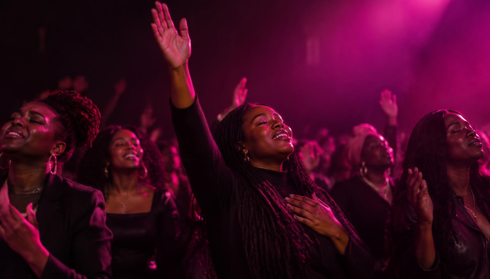 Women worshipping together under hot pink lights